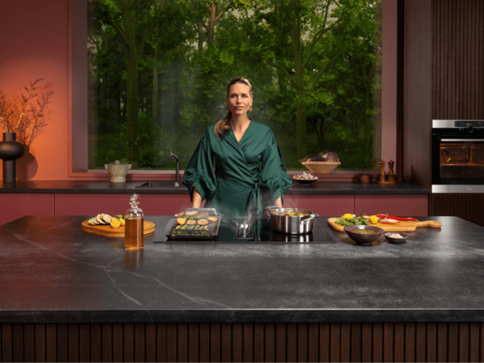 Woman standing next to hob in kitchen